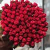 100 Red Roses Grande Bouquet close-up: rows of bright red roses held against a dark background