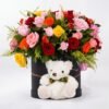 Colorful Flower Box: red, pink, orange and yellow roses with solidago in a black round box with a white teddy bear in front