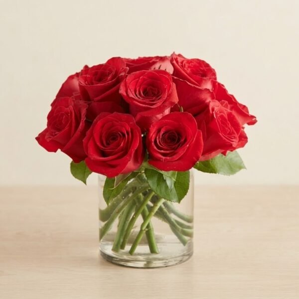 Crimson Elegance Vase, a compact dome of red roses with leaves in a short clear glass vase