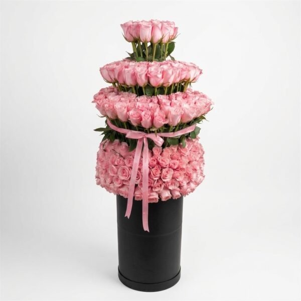 Blush Rose Royal Box: tall tiered arrangement of light pink roses on a black round box, tied with a pink satin bow