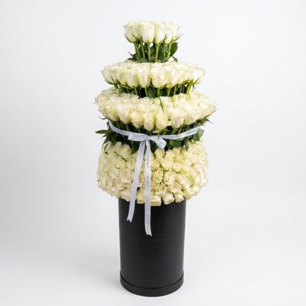 White Rose Royal Box: tall tiered arrangement of white roses on a black round box, tied with a silver satin bow